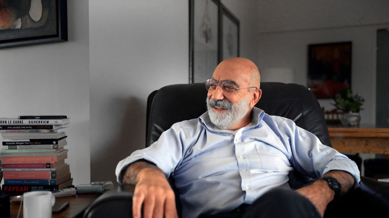 El escritor y periodista turco Ahmet Altan sonríe durante una entrevista en su apartamento en Estambul, en enero de 2022. Recién liberado, tras cinco años de prisión por su supuesto involucramiento en un fallido golpe de Estado, a sus 71 años ahora cuenta el tiempo en los libros que falta escribir. Foto: BULENT KILIC / AFP.