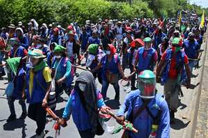 Colombian indigenous people taking part in a "Minga" (indigenous meeting) walk along the Pan-American highway as they arrive in the city of Cali with the expectation of meeting President Ivan Duque, on October 12, 2020. - Thousands of indigenous people arrived in Cali where they hope to meet with President Duque, after having summoned him through a letter in recent days, in which they express concern about the increase of violence due to the presence of armed groups in their territories, the murder of indigenous and social leaders, and the recent massacres. (Photo by Luis ROBAYO / AFP)