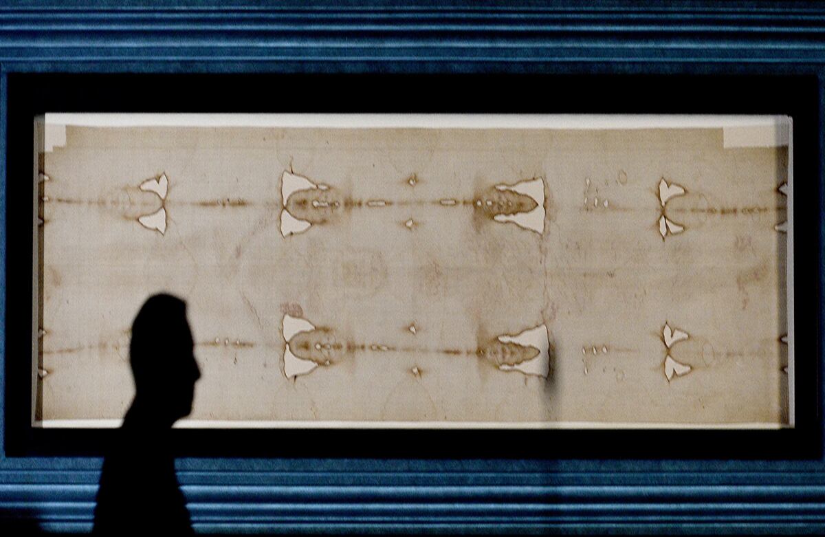 Un hombre pasa por el Santo Sudario, una pieza de lino que contendría las marcas de crucifixión de Jesús y que reposa en la Catedral de Turín. El público lo podrá visitar hasta el 24 de junio, en Turín, Italia. (AP)