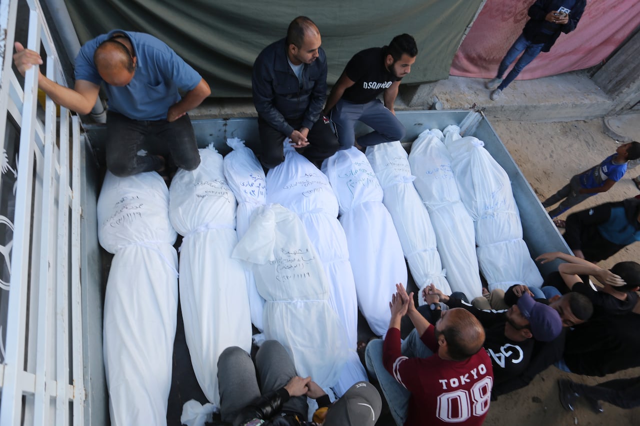 Palestinos sentados junto a los cuerpos de la familia Hijazi que murió en el bombardeo israelí de la Franja de Gaza en Rafah el viernes 10 de noviembre de 2023.