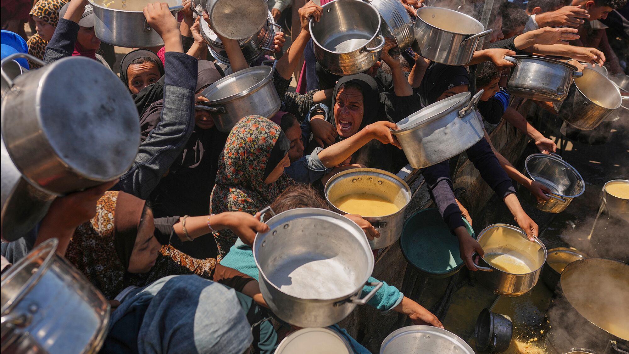 Los palestinos luchan por conseguir comida donada en una cocina comunitaria en la ciudad de Gaza, al norte de la Franja de Gaza. Lunes 4 de agosto de 2025.
