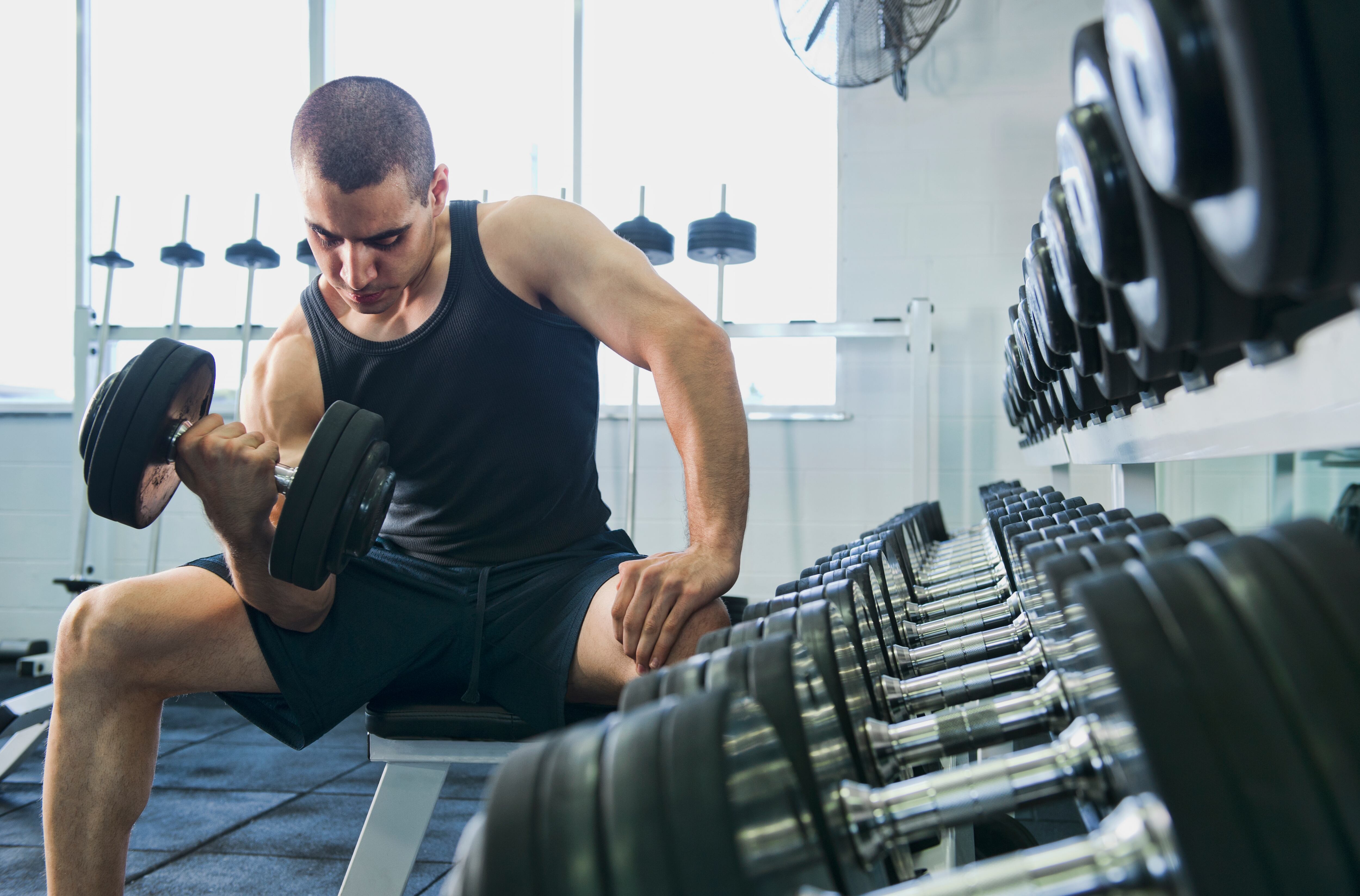 Hombre en el gimnasio realizando ejercicios para fortalecer los bíceps