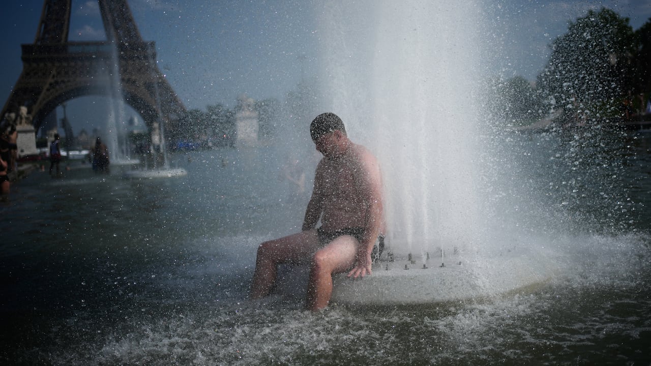 Una persona se refresca en la fuente del Trocadero, cerca de la Torre Eiffel, durante una ola de calor en París.
