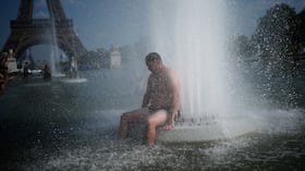 Una persona se refresca en la fuente del Trocadero, cerca de la Torre Eiffel, durante una ola de calor en París.