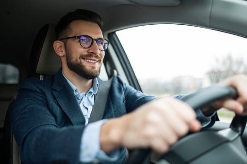 Hombre con gafas manejando un carro.