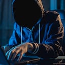 El programador hacker anónimo usa una computadora portátil para hackear el sistema en la oscuridad. Creación e infección de virus maliciosos. El concepto de base de datos de ciberdelincuencia y piratería