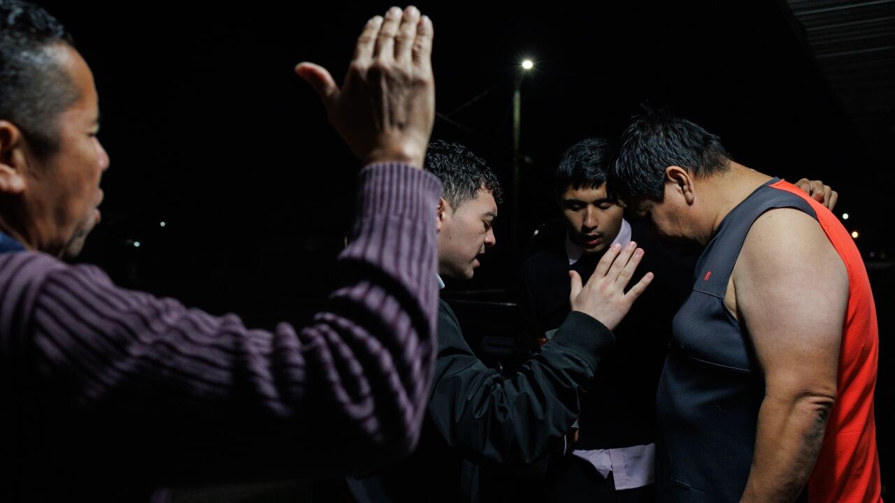 Miembros de la comunidad rezan con un residente de un barrio mayoritariamente inmigrante