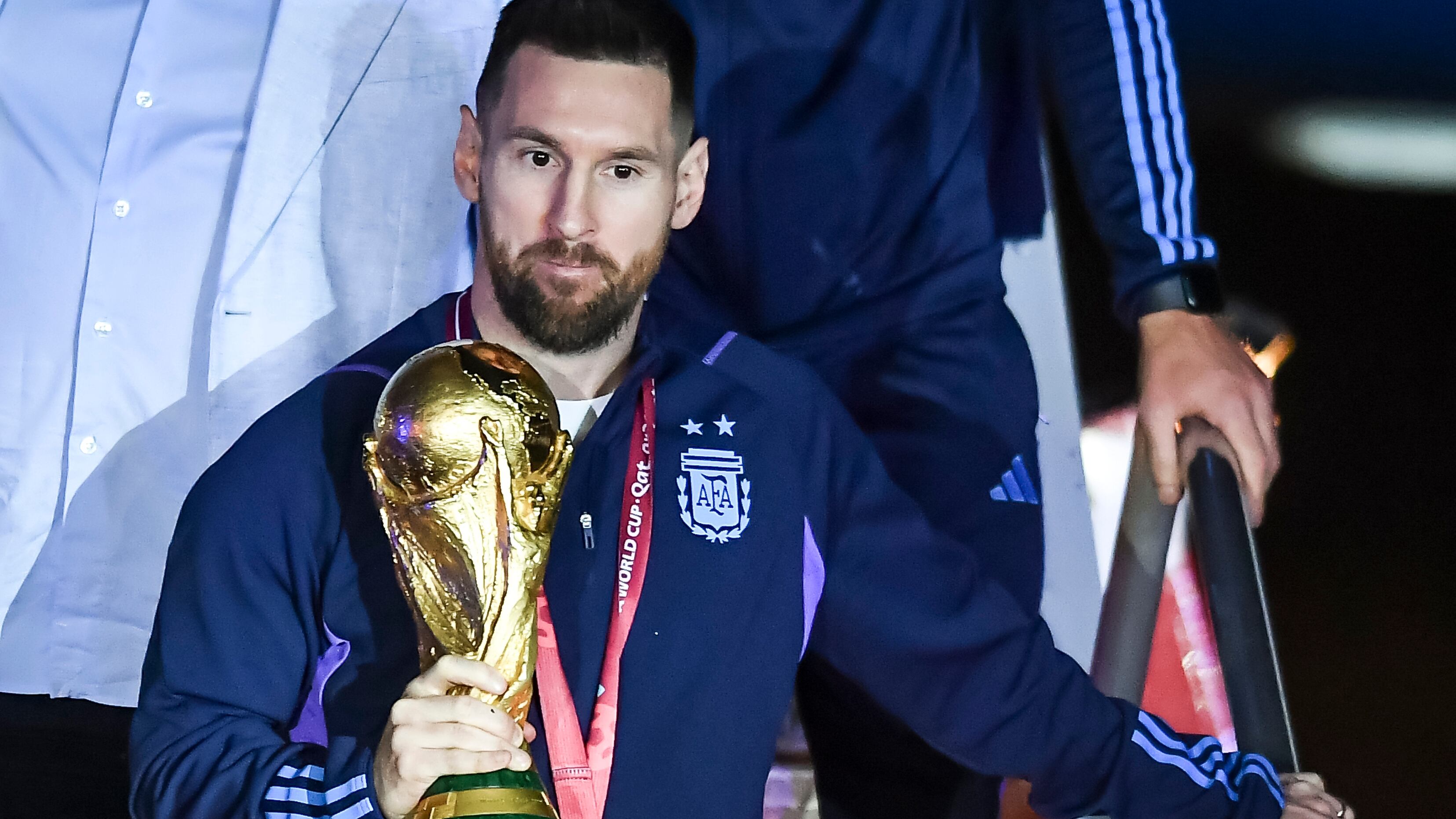 Lionel Messi sostiene el trofeo del Mundial de Fútbol a su llegada a Argentina.