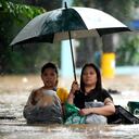 Los residentes protegen sus pertenencias mientras caminan por una calle inundada causada por las fuertes lluvias de la tormenta tropical Yagi, llamada localmente Enteng, en Cainta, provincia de Rizal, Filipinas, el lunes 2 de septiembre de 2024. (Foto AP/Aaron Favila)
