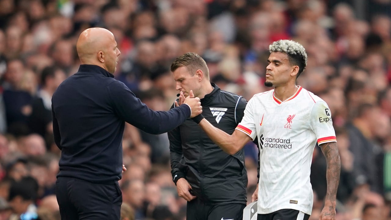 Arne Slot choca sus manos con Luis Díaz durante el partido entre Manchester United y Liverpool.