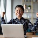 Eufórico joven estudiante india ganadora celebrar victoria triunfo sentarse en casa escritorio con computadora portátil ganar fortuna en línea sentirse emocionado obtener nueva oportunidad de trabajo buen examen resultado gran concepto de noticias.