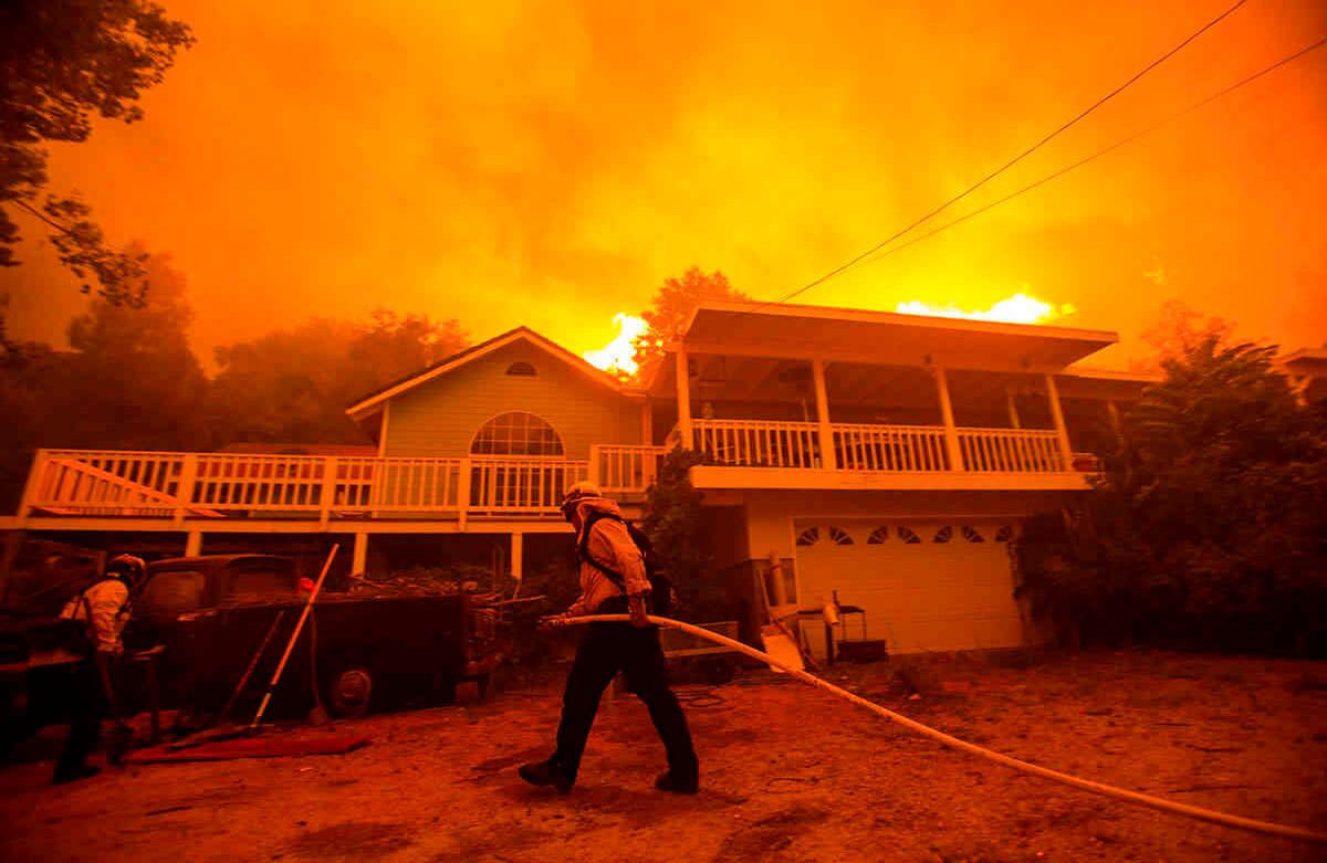 Los bomberos trabajan cerca de una casa mientras el incendio del lago Hughes arde en el fondo, en el Bosque Nacional Ángeles, al norte de Santa Clarita, California. Foto: Ringo H.W. Chiu / AP 