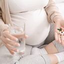 Vitamins for pregnant Expectant woman holding bunch of pills and glass of water, closeup
