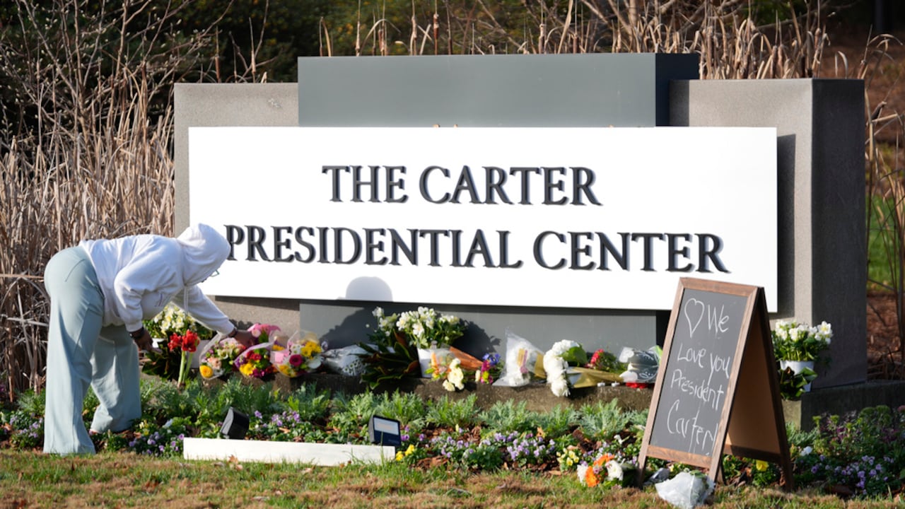 Christine Mason, de Atlanta, coloca flores a la entrada del Centro Presidencial Jimmy Carter el lunes 30 de diciembre de 2024, en Atlanta. El expresidente Carter falleció el domingo en su casa en Plains, Georgia, a la edad de 100 años. (AP Foto/John Bazemore)