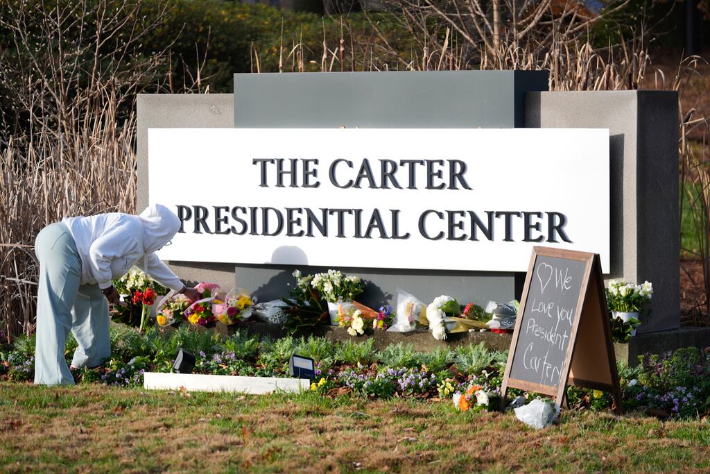 Christine Mason, de Atlanta, coloca flores a la entrada del Centro Presidencial Jimmy Carter el lunes 30 de diciembre de 2024, en Atlanta. El expresidente Carter falleció el domingo en su casa en Plains, Georgia, a la edad de 100 años. (AP Foto/John Bazemore)