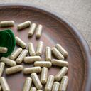Close up biotin capsules and bottle on clay brown plate on burlap background. Dietary supplements for healthy skin, hair, nail. Vitamins and minerals for vegans and vegetarians. Superfood