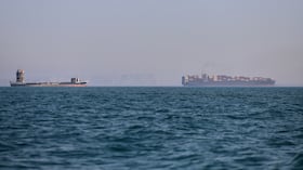 Un buque portacontenedores (a la derecha) y otro barco de carga pueden apreciarse en el estrecho de Ormuz, frente a Bandar Abbas, Irán.