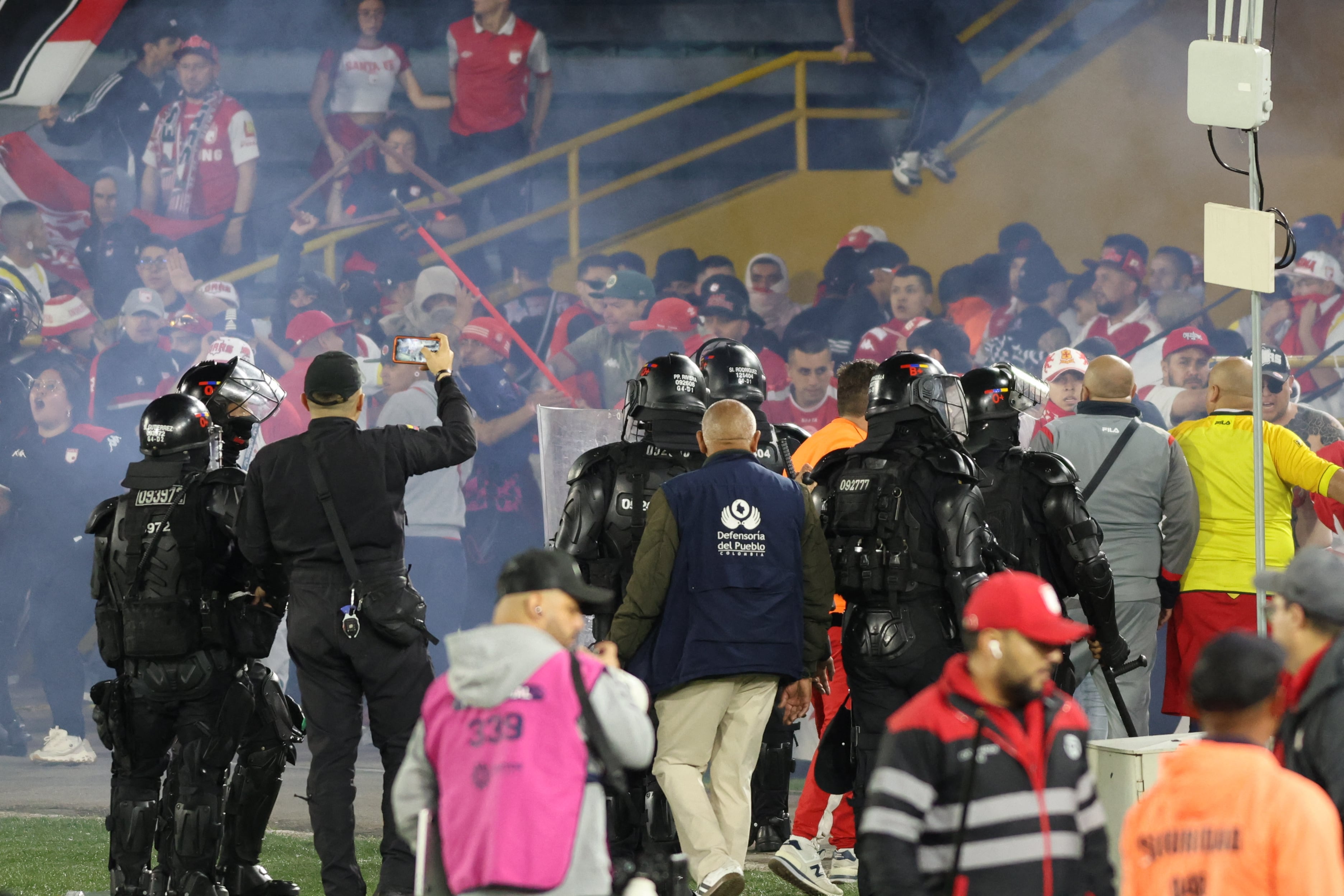 Fans of Santa Fe and America de Cali clash on the pitch during the Colombian league match between the two teams at the Nemesio Camacho El Campin Stadium in Bogota, Colombia, on August 22, 2026. (Photo by Daniel Garzon Herazo/NurPhoto) (Photo by Daniel Garzon Herazo / NurPhoto via AFP)