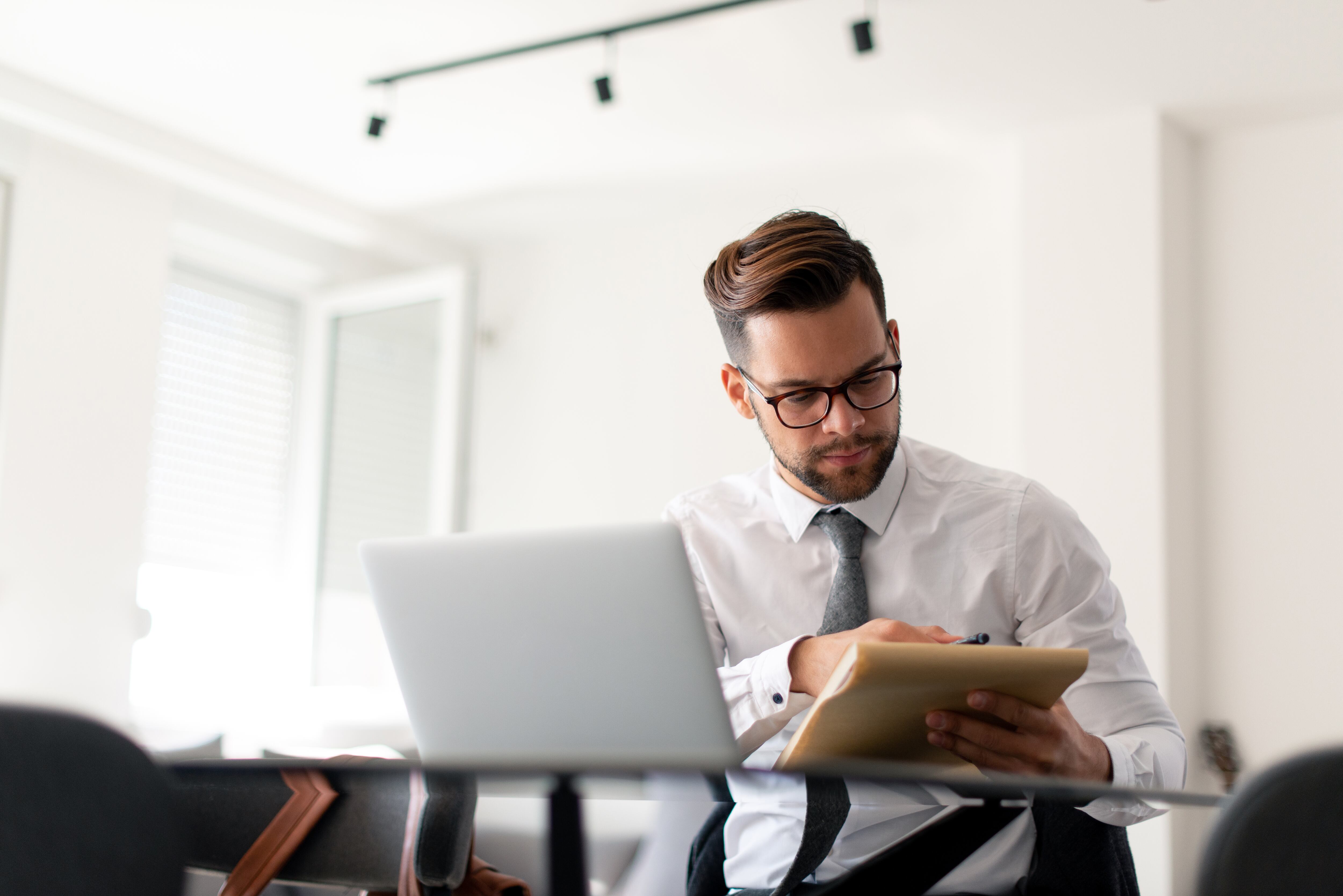 Chico joven vestido formalmente está trabajando en la computadora portátil desde casa.