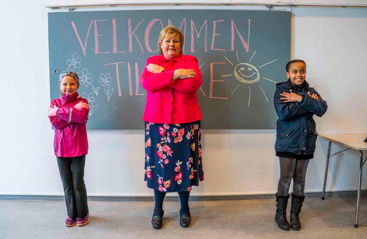 La primera ministra noruega, Erna Solberg (centro) aprende una técnica de saludo de los estudiantes Celine Busk, izquierda y Rim Daniel Abraham, durante su visita a la escuela Ellingsrudasen en Oslo, el pasado lunes 27 de abril de 2020. Las escuelas volvieron a abrir de primero a cuarto grado en Noruega después de seis semanas de cierre, debido a la pandemia del coronavirus. (Hakon Mosvold Scanpix de Larsen / NTB AP)