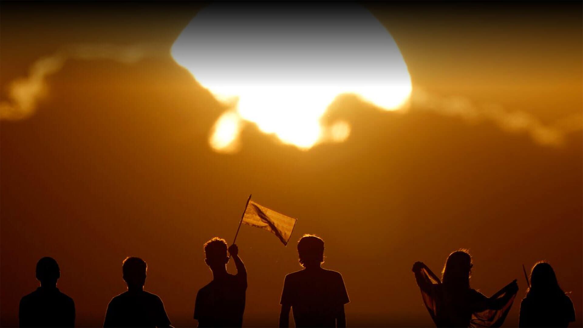 La gente sostuvo banderas y saludó a los automovilistas que pasaban para conmemorar el aniversario de los ataques del 9-11 desde un paso elevado de la autopista, mientras se ponía el sol el miércoles 11 de septiembre de 2024.