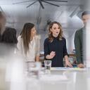 La directora ejecutiva de una empresa nueva reúne a su equipo multiétnico alrededor de la mesa de conferencias para finalizar el lanzamiento de un producto. Ella está firmando documentos y sus compañeros de trabajo están mirando a su lado.