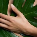 Woman holding leaf in front of chest, cropped.
