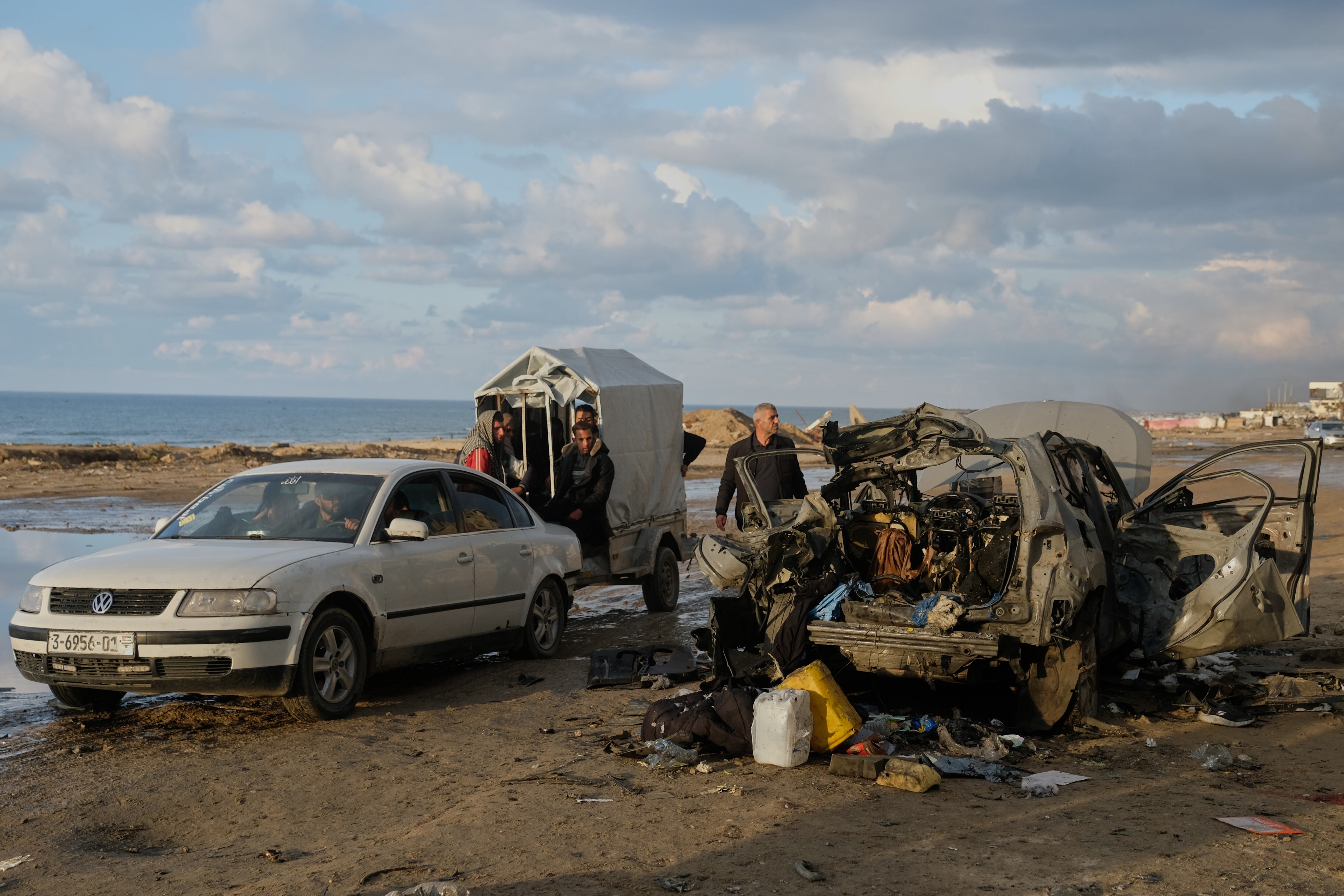 Palestinos observan un automóvil destruido tras un ataque israelí en la ciudad de Gaza.