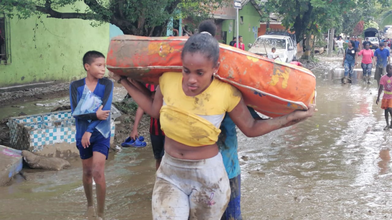 Una mujer camina por el lodo mientras ayuda a sacar las cosas que se salvaron por la inundación