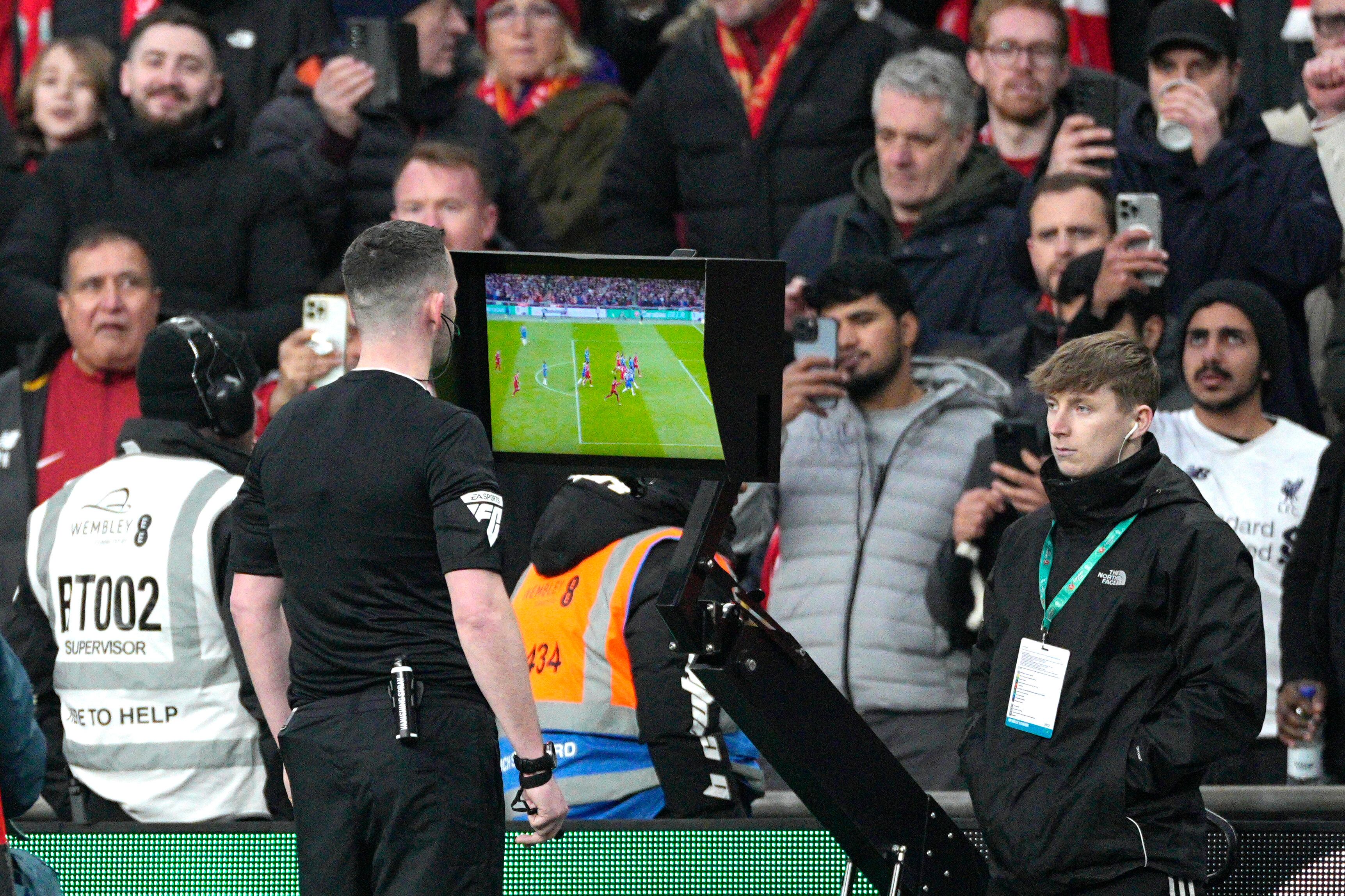 Referee Chris Kavanagh pauses the match and asks for the VAR to check on a possible goal during the English League Cup final soccer match between Chelsea and Liverpool at Wembley Stadium in London, Sunday, Feb. 25, 2024. (AP Photo/Dave Shopland)