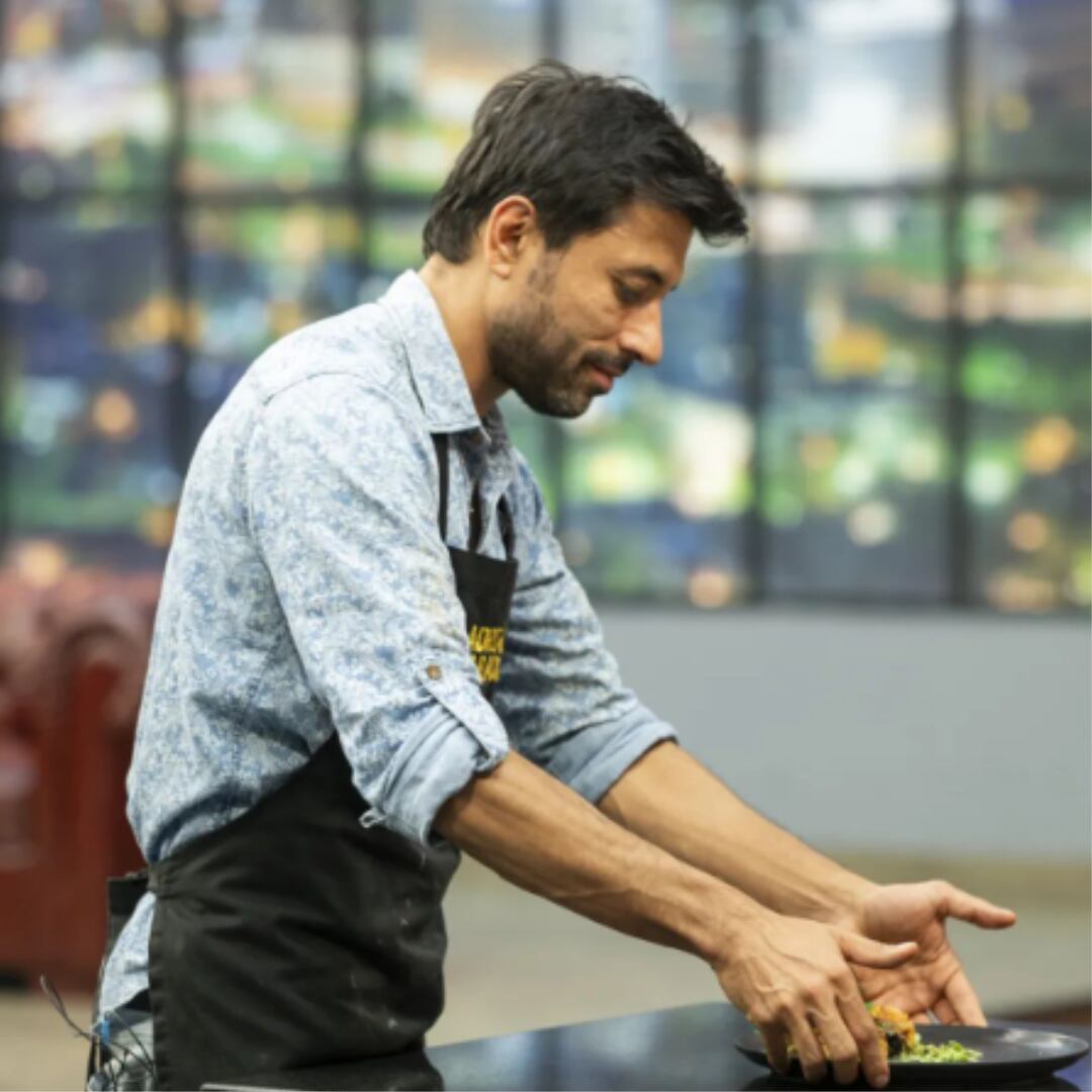Adrián Parada presentando su plato vestido con delantal negro.