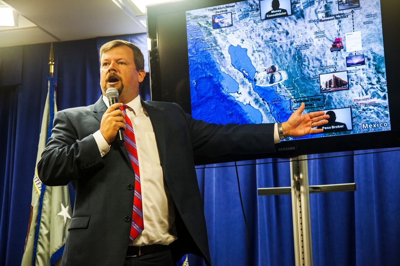 Robert E. Dugdale, Fiscal Federal Auxiliar, Jefe de la División Penal, con una captura de pantalla del plan de lavado de dinero "Peso Negro". Conferencia de prensa en el Edificio Federal de Los Ángeles para anunciar una redada multigubernamental y de agencias policiales en negocios del centro de Los Ángeles vinculados con muchos lavados para los cárteles de la droga. Más de 1000 agentes del orden entregaron órdenes de búsqueda y arresto a empresas sospechosas de utilizar esquemas de "mercado negro de cambio de pesos" para lavar dinero para la droga de Sinaloa