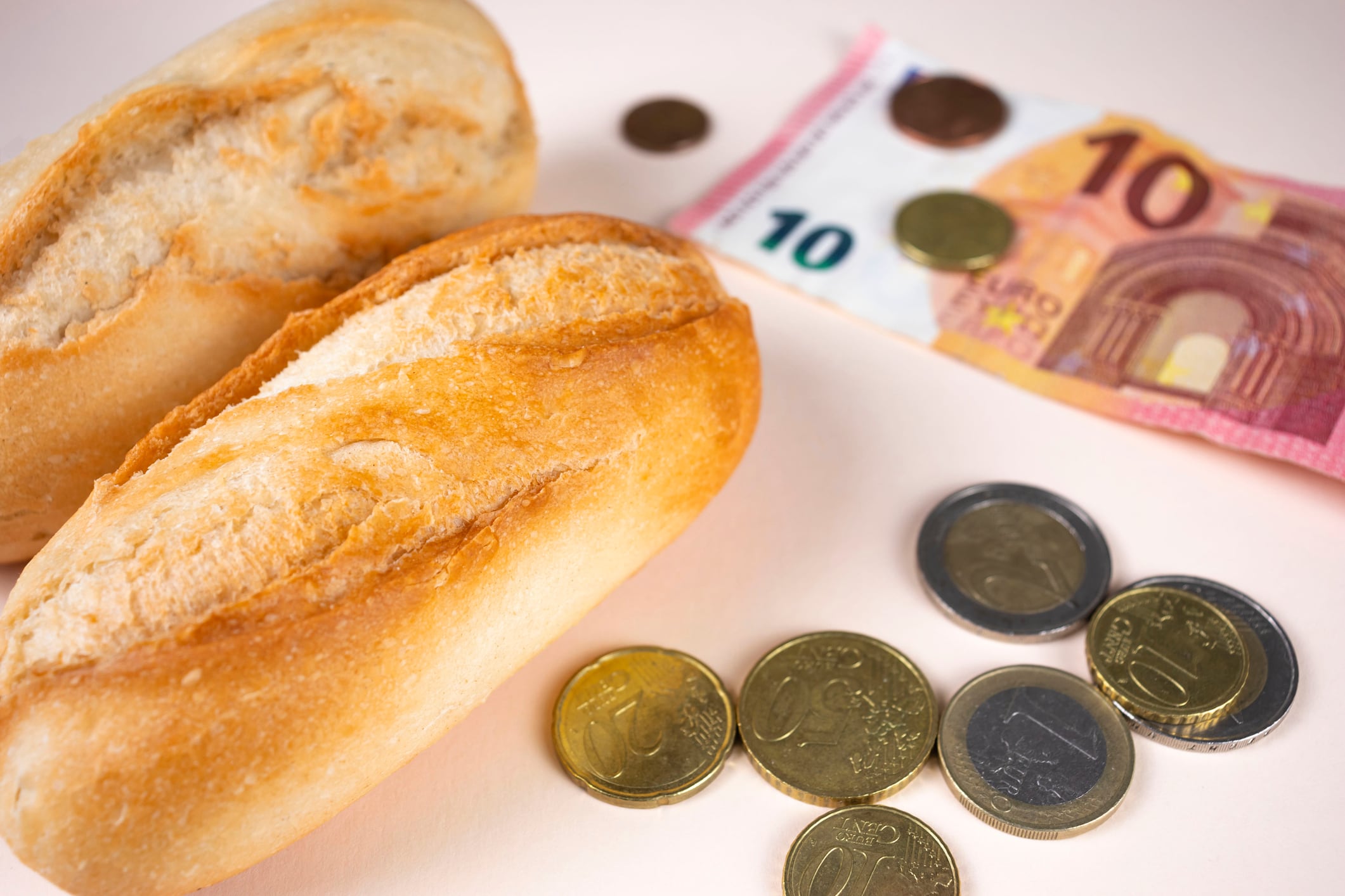 Precio del pan, pan blanco con dinero y monedas en euros. Alimentos caros por inflación, subida de precios y crisis alimentaria