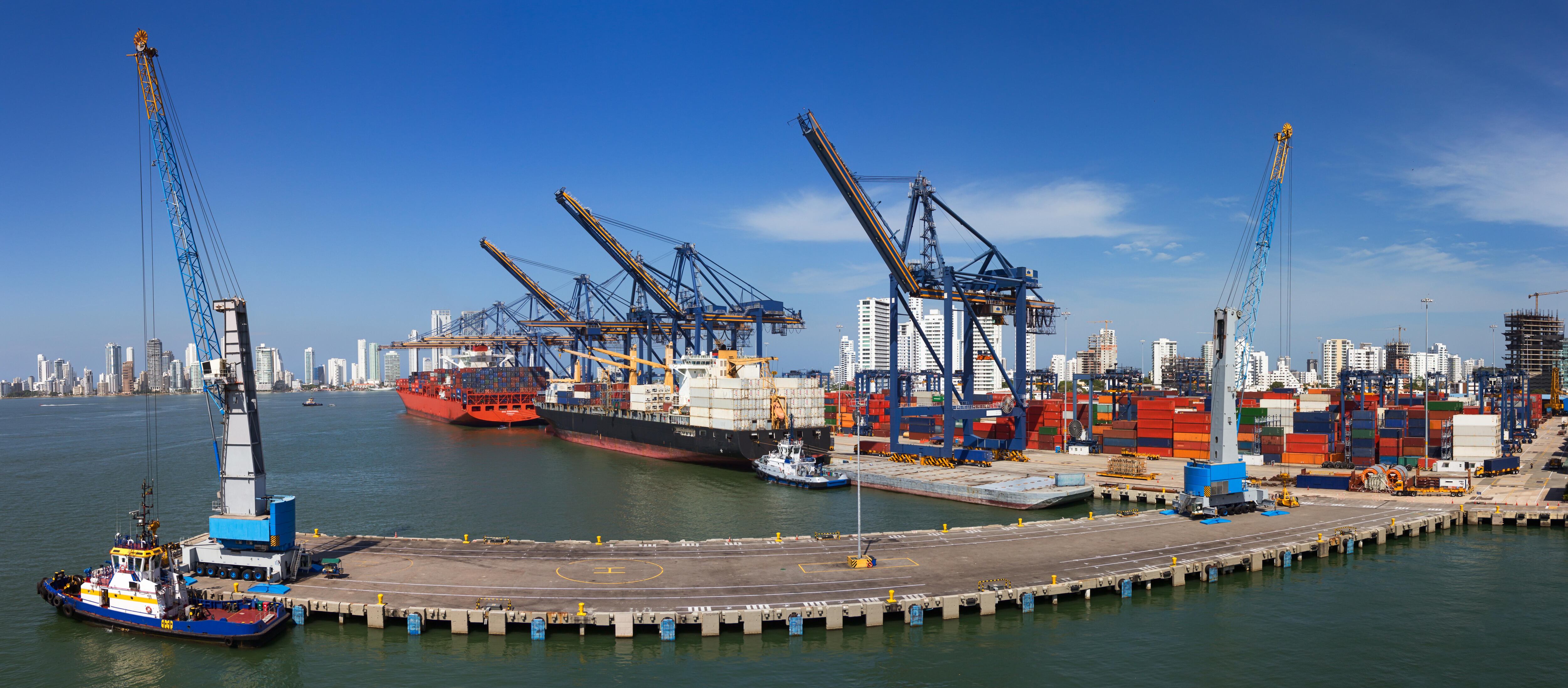 Vista panorámica de una actividad portuaria con cargueros, grúas y contenedores en el muelle del Puerto de Cartagena, Colombia.