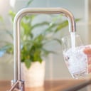 Llenar un vaso con agua potable del grifo de la cocina