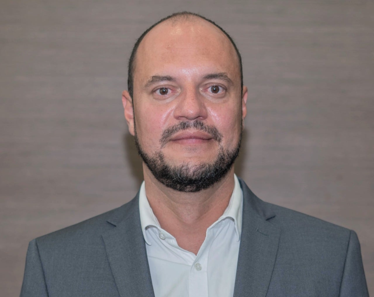 Hombre con barba y poco pelo encorbatado en plano medio.