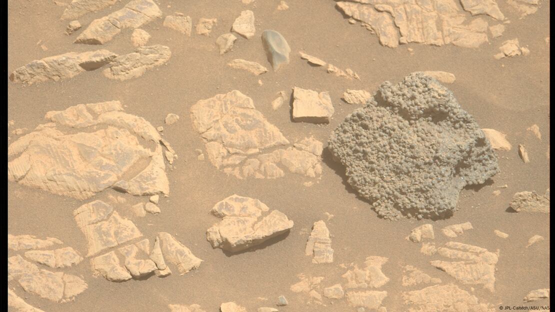 Científicos barajan teorías sobre una roca marciana con esferas, que podría haberse formado por actividad volcánica o impactos de meteoritos.