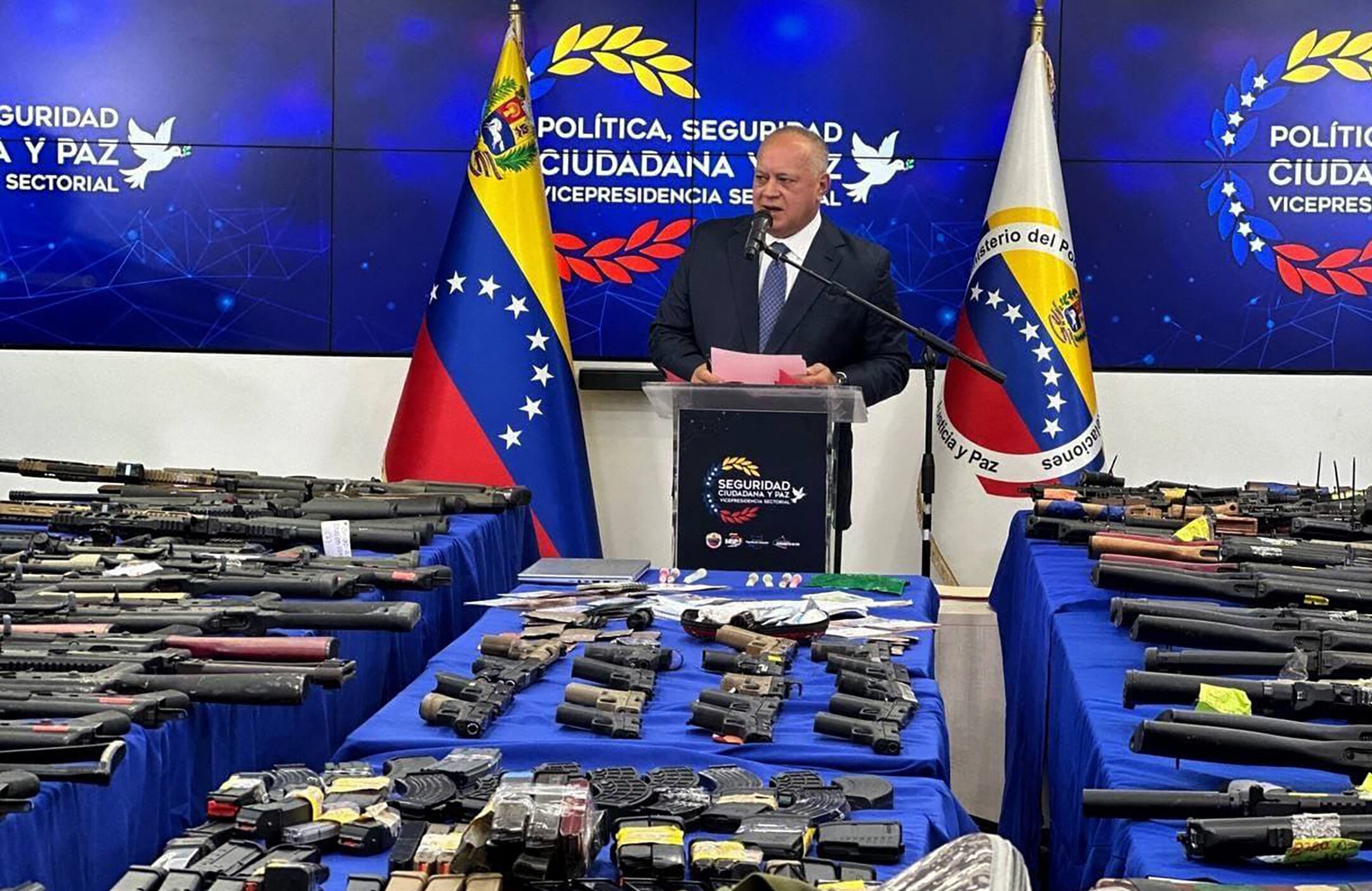 Esta imagen publicada por el Ministerio del Interior y de Justicia de Venezuela muestra al Ministro del Interior de Venezuela, Diosdado Cabello, dando una conferencia de prensa junto a las armas incautadas en exhibición en Caracas el 14 de septiembre de 2024. Tres ciudadanos estadounidenses, dos españoles y un ciudadano checo han sido detenido en Venezuela bajo sospecha de conspirar para desestabilizar el país mediante "acciones violentas", dijo el gobierno, agregando que se habían incautado cientos de armas.