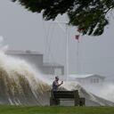 Esta fotografía muestra a un hombre que toma fotografías frente a grandes olas en la orilla del lago Pontchartrain, en Nueva Orleans, el domingo 29 de agosto de 2021. (AP Foto/Gerald Herbert)