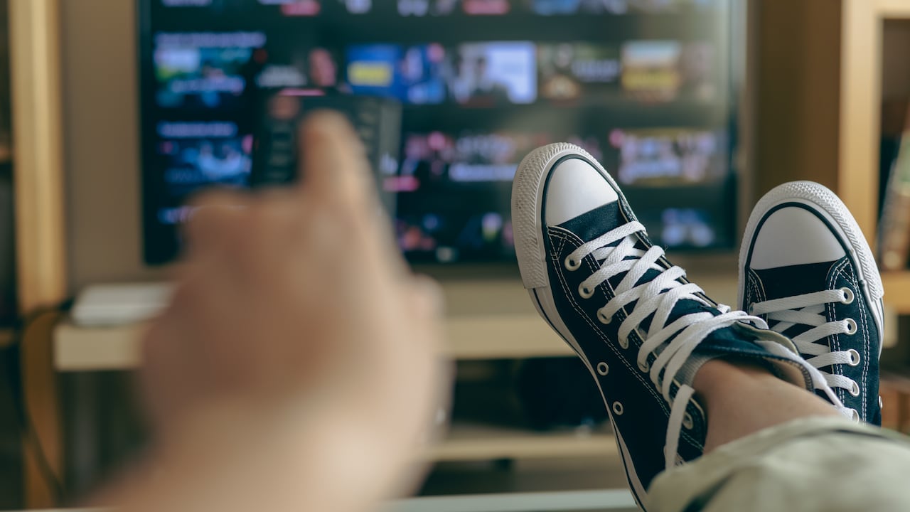 Persona relajada en casa viendo la televisión.