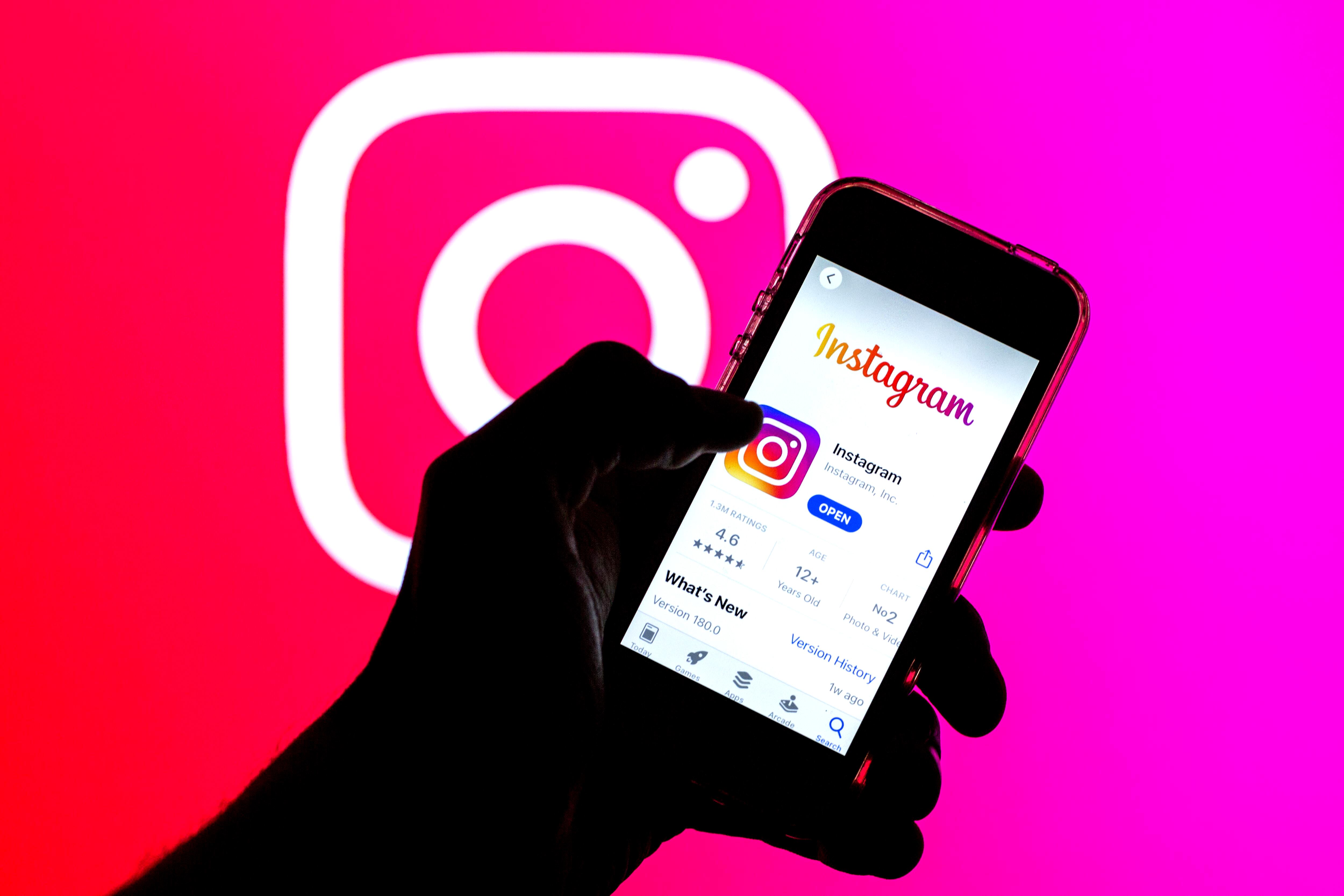 En esta ilustración fotográfica, la aplicación de Instagram en la App Store mostrada en la pantalla de un teléfono inteligente y un logotipo de Instagram en el fondo.