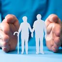 Figuras recortadas de la pareja de ancianos que protegen la mano sobre fondo azul