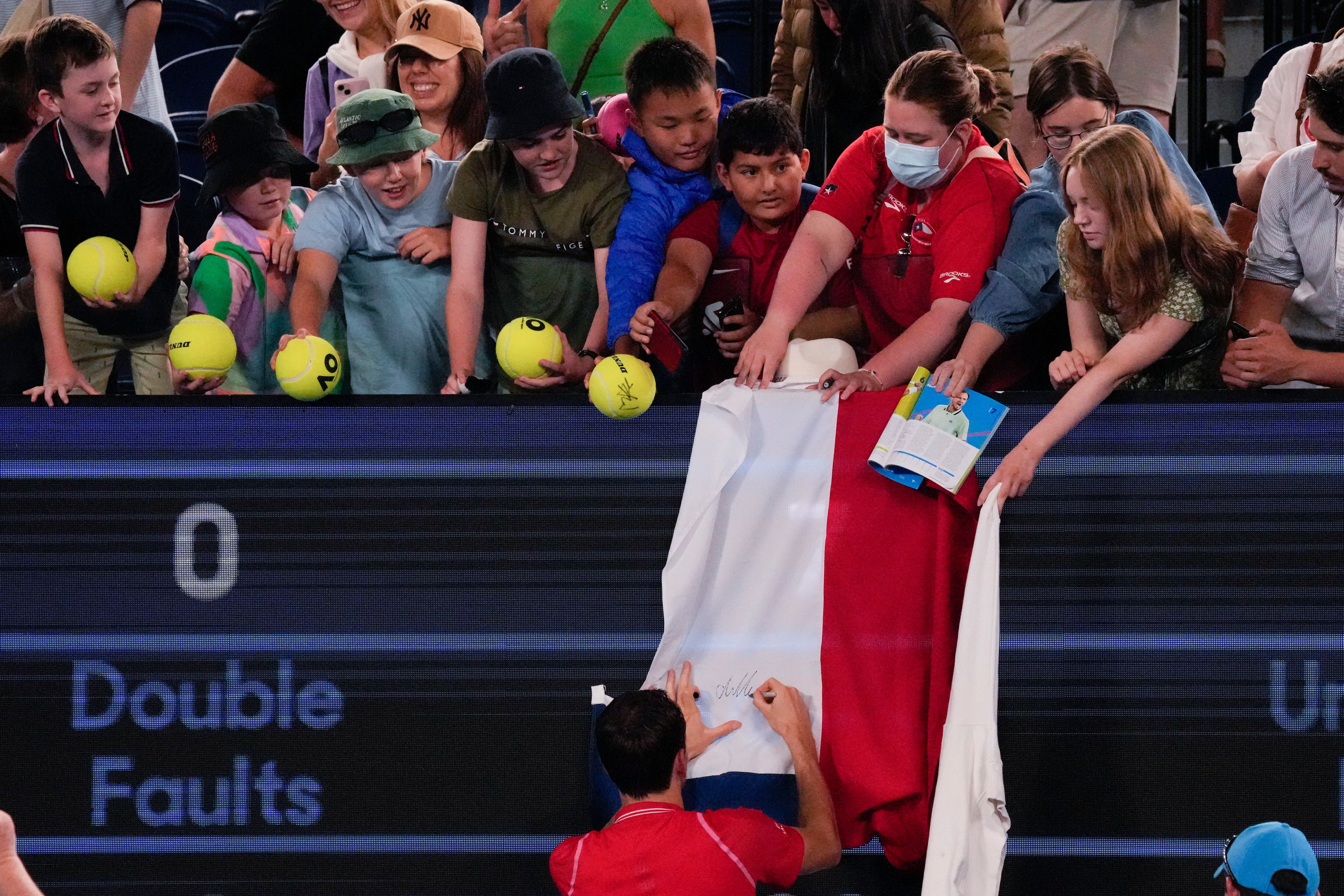 Daniil Medvedev of Russia autographs a Russian flag after defeating Marcos Giron of the U.S. in their first round match at the Australian Open tennis championship in Melbourne, Australia, Monday, Jan. 16, 2023. (AP Photo/Aaron Favila)