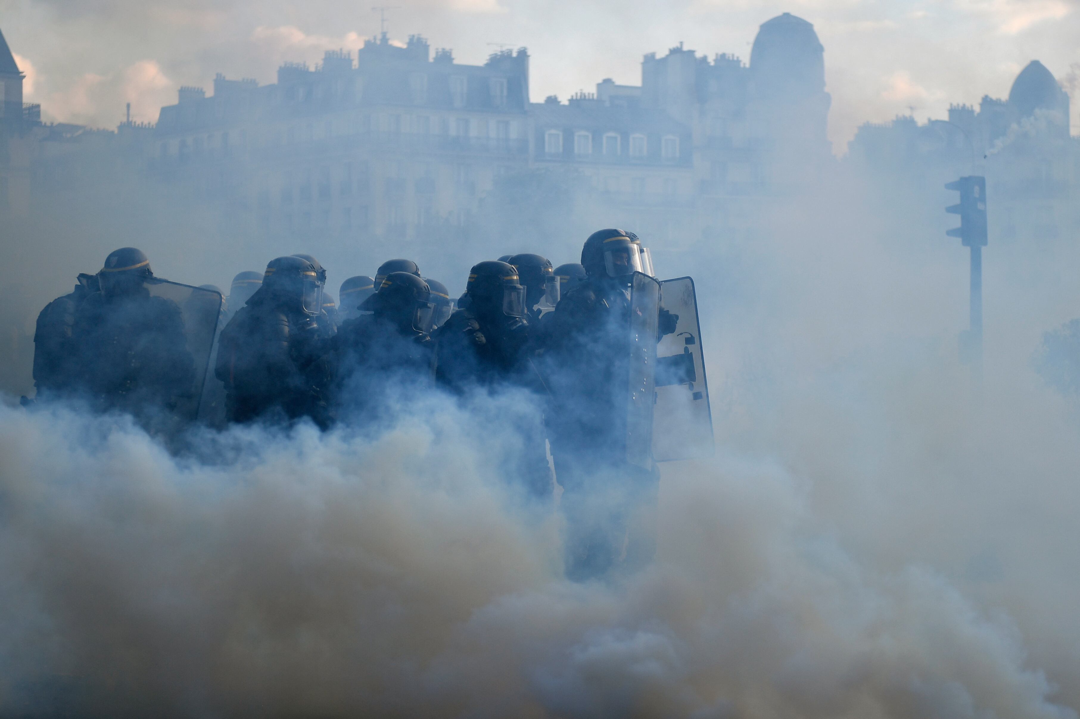 Cuerpo de Seguridad Republicano Francés (CRS - Compagnies republicaines de Securite) policías, rodeados de gases lacrimógenos, toman posición en la Place de la Nation durante una manifestación el Primero de Mayo (Día del Trabajo), para conmemorar el día internacional de los trabajadores, más de un mes después de que el gobierno impulsara una impopular ley de reforma de las pensiones en el parlamento, en París, el 1 de mayo de 2023. - Los partidos de oposición y los sindicatos han instado a los manifestantes a mantener su campaña de tres meses contra la ley que elevará la edad de jubilación a los 64 años. 62. (Foto de JULIEN DE ROSA / AFP)