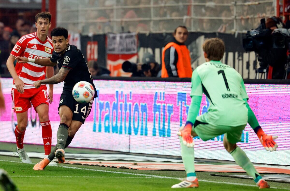 El delantero colombiano del Bayern Munich #14 Luis Díaz (C) anota el primer gol de su equipo ante el portero danés del Union Berlin #01 Frederik Ronnow.