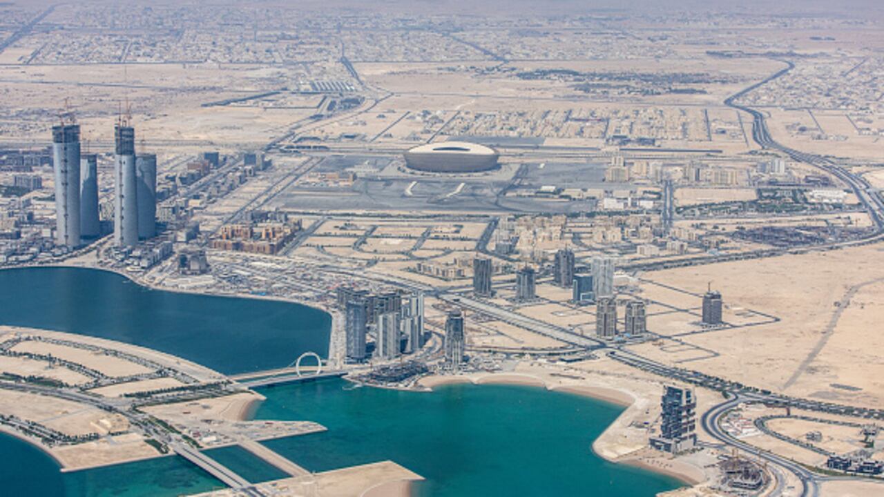 El estadio de fútbol de Lusail, sede de la próxima Copa Mundial de la FIFA 2022, más allá de los rascacielos residenciales y comerciales en Doha, Qatar, el lunes 20 de junio de 2022. Se esperan alrededor de 1,5 millones de aficionados, un poco más de la mitad de la población de Qatar. para descender sobre el pequeño estado del Golfo para el torneo de fútbol de la Copa Mundial de la FIFA de este año. Fotógrafo: Christopher Pike/Bloomberg vía Getty Images