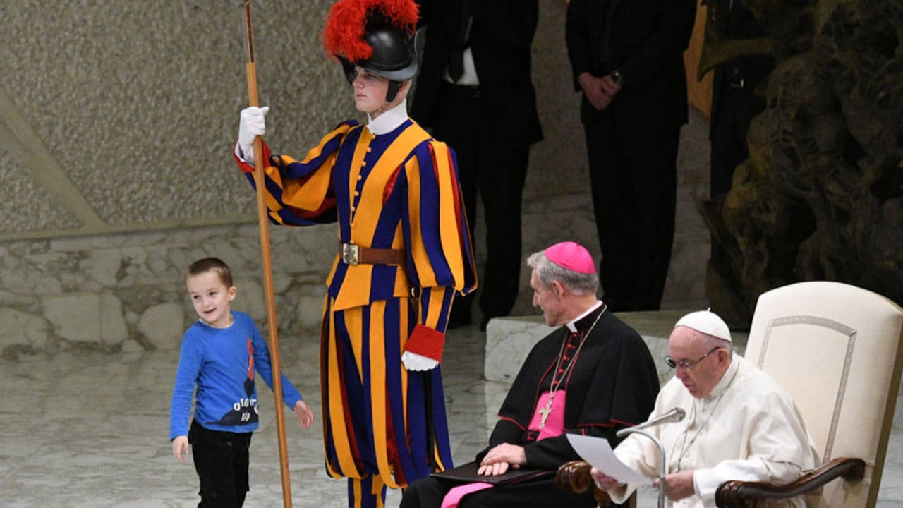 Un niño juega con un miembro de la guardia suiza en la sala de audiencias Pablo VI, en el Vaticano.