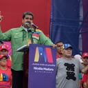 la ex estrella del fútbol argentino Diego Maradona (R) sostiene la bandera venezolana mientras el presidente venezolano, Nicolás Maduro, pronuncia su último discurso de campaña.