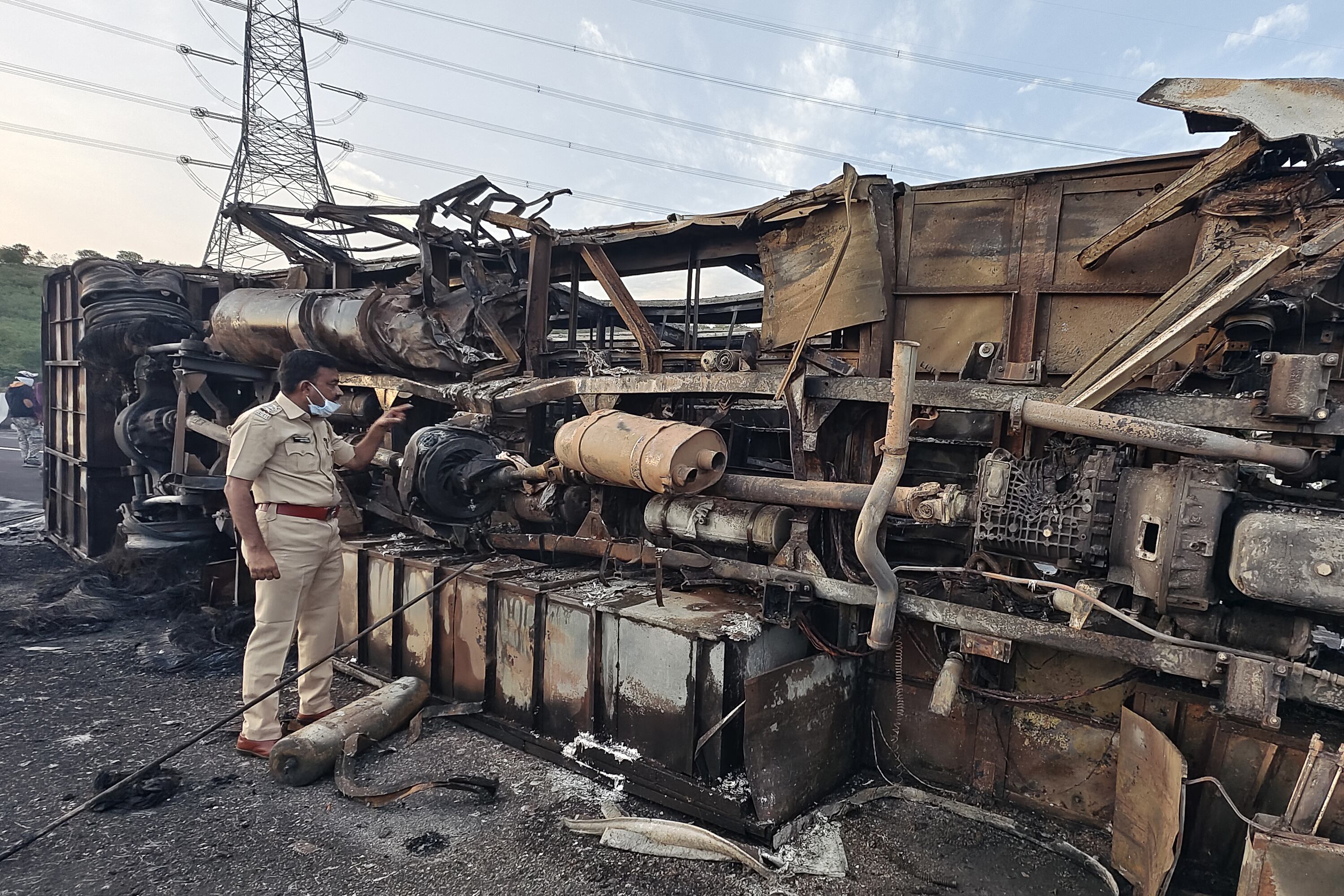 Un policía inspecciona los restos de un autobús que se incendió a lo largo de la autopista Samruddhi cerca de Sindkhed Raja en el distrito de Buldhana del estado de Maharashtra el 1 de julio de 2023. Al menos 25 personas murieron y otras ocho resultaron heridas después de que un autobús se incendiara durante la noche en una autopista en El estado indio de Maharashtra, dijo la policía el 1 de julio. (Foto de Gajanan MEHETRE / AFP)