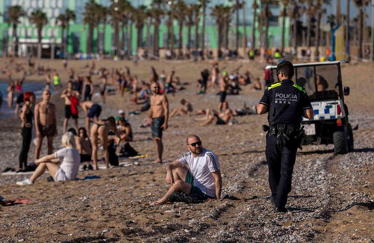 Los oficiales de policía les piden a las personas que no se sienten mientras patrullan en la playa de Barcelona, España. Miércoles 20 de mayo de 2020. Barcelona permitió el miércoles que la gente caminara sobre sus playas por primera vez desde el inicio del bloqueo del coronavirus desde dos meses. (Foto AP / Emilio Morenatti)